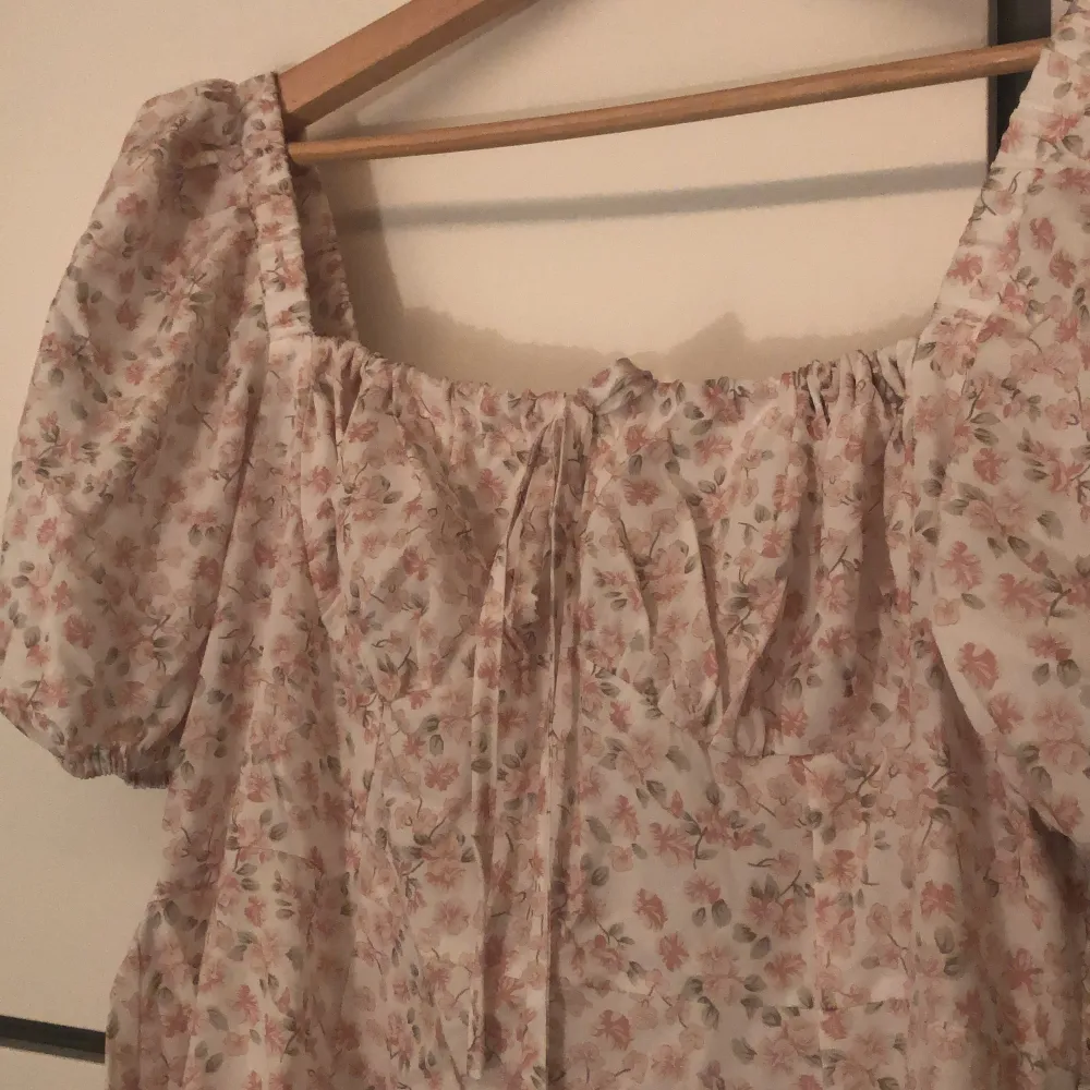 Vit midi klänning med rosa blommor och slits på en sida. Helt ny aldrig använt pris lappen är kvar :). Mekot.