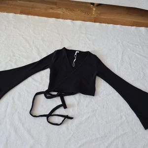 Kort omlott kofta - Kort svart omlott kofta med trumpetärmar