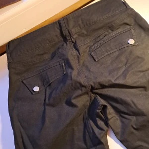 Snygga byxor (36 som lite vida- annars stlk 38/M) - Carrot-byxa (lite smalare vid anklarna). med 3 knappar i silverfärg på varsin framficka, samt en på bakfickorna (se bilder). Hade behållt men för små. Mycket sköna. Mycket lite använda.   Färg: Svart  Frakt tillkommer.