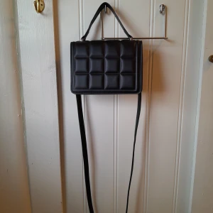 Väska - Svart-rutig axelremsväska i fint skick. Postar spårbart