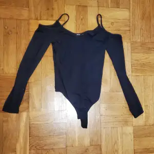 Svart långärmad body med cutout för axlar och smala axelremmar från Bikbok. Stretchigt material. Okej att komma med bud. Katt i hemmet. 