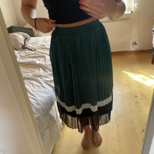 Plisserad långkjol - Superfin långkjol med plissering i mörkgrönt, vitt och svart. Svart innekjol finns och stretchigt gummiband i midjan. Hör av dig vid frågor 💕
