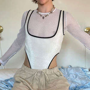 Vit svart sammet body y2k 2000s 00s  - Vit sammet body med svarta kanter ⛸ Så snygg för fest eller utekväll när man vill vara mer out there! Perfekt med en långärmad under, kanske till och med en fishnet! Det bästa med denna bodyn är att sammeten gör att den glittrar lite!