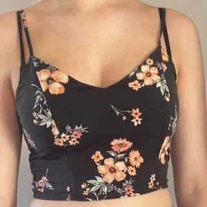 Svart blommig topp - Jättesöt svart topp med rosa blommor. Fin knytdetalj i ryggen. Bra skick, säljs pga inte min stil <3