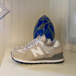 New Balance-574 - Vita sneakers med storlek 38. Köpta april 2022, inte använda mycket (eftersom jag har storlek 39). Detta innebär att dem fortfarande är i gott skick och sulan har ursprunglig form. Ursprungligt pris 1 095 kr.