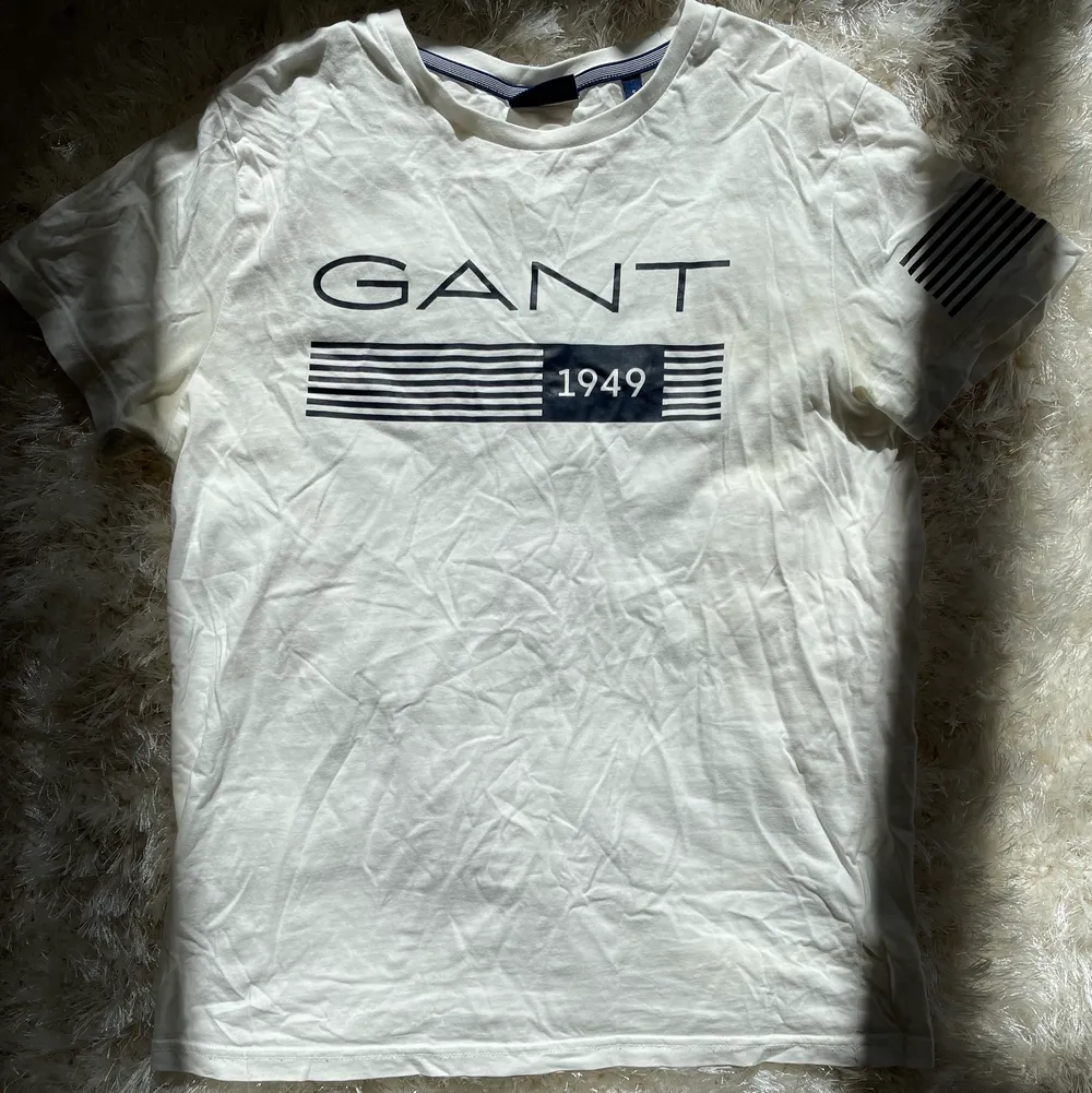 Vit t-shirt från GANT med marinblått tryck. Tröjan är i nyskick och har endast används ett fåtal gånger. . T-shirts.