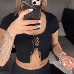 T shirt  - En svart t shirt med knytningar vid mitten. Storleken xs men passar även s. 