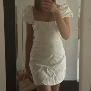 Vit klänning med öppen rygg och puffärm - Säljer denna otroligt söta vita klänningen! Den är endast använd en gång men är lite skrynklig på bilderna då den legat ovikt ett tag, men när men strykt den är den gott som lika söt igen! Är du intresserad finns bättre bilder! Sitter lika bra på en med S
