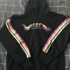 Svart/regnbåge hoodie - Vill sälja min lilla systers hoodie som hon it vill ha längre. En text på framsidan och några färger på armarna, igentligen så är den för en 13/14 åring tjej men skulle även säga att den passar 11/12 åringar. Helt ok skick, och väldigt skön material 