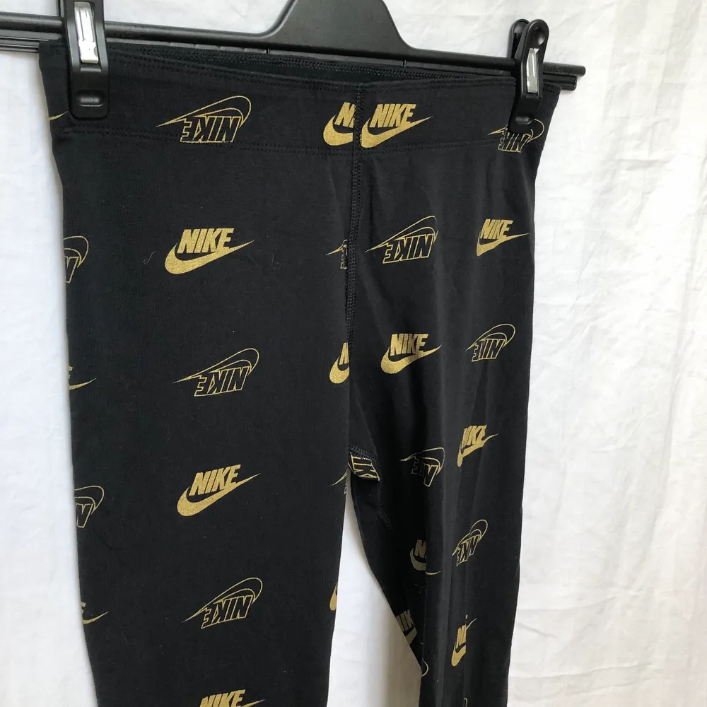 Svarta Nike leggings med guld loggor. Aldrig använda.. Jeans & Byxor.