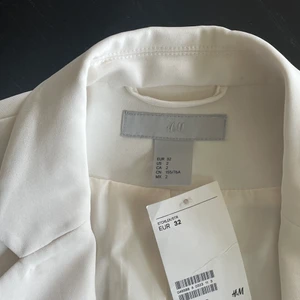 Vit kavaj - Helt vit kavaj från HM (det är samma modell som på andra bilden men i första bildens vita färg!) Storlek 32, aldrig använd! Kavajen har en svart knapp. Hör av er för fler bilder eller vid någon fråga!