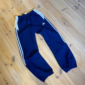 Vintage Adidas Byxor - Mörkblåa polyester byxor från märket adidas. As feta, loosefit, condition 7/10. Storlek 11-12 yrs, men passar som XS, rekommenderar till folk under 165 cm. För fler bilder eller mått kontakta mig 😊 frakt sker via PostNord spårbart 57 kr 📦