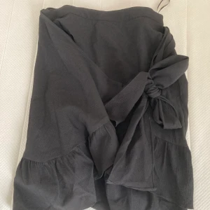 Kjol från Vero Moda storlek XS - Svart kjol som knyts i midjan, oanvänd. Storlek XS, skriv för fler bilder. Kom med bud 
