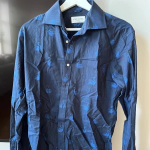 John Henric Blå Skjorta Strl 38/M - Skitsnygg John Henric Skjorta med sydda svanar överallt, Storlek 38 ≈ Medium