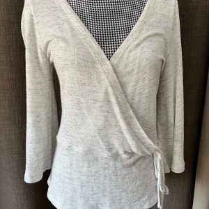 Omlottröja i stl.M - Ljusgrå omlottröja i stl.M  Fint skick utan fläckar eller hål. Använd en gång