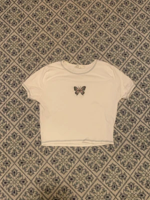Fjärilstopp - Topp från Bershka. Aldrig använd. Detaljer i sömmarna och med en fin fjäril i mitten. 