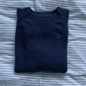 En marinblå stickad tröja från Tommy Hilfiger i storlek XS/S - En marinblå, stickad tröja från Tommy Hilfiger. Tröjan är i storleken 16-18 för barn och motsvarar XS/S i dam. Tröjan är lite urtvättat vid halsen (se bild) men i övrigt i bra skick! (samfraktar gärna)
