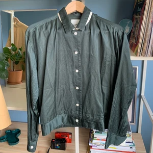 Tunn jacka från Wood Wood - Jättefin tunn jacka från Wood Wood i modellen Larisa Jacket, storlek 42 men inte superstor i modellen!  45% bomull och 55% viskos Använd, men i ok skick! En liten liten röd fläck på framsidan som man kan se på första bilden. Perfekt nu på sommaren! 🌼