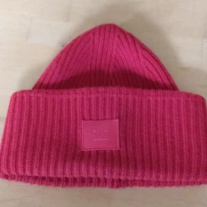 Acne Studios Mössa röd - Jag vann mössa i en Tisetävling men tycker inte riktigt om hur den sitter på mig. Den är i nyskick, jag har bara använt den en handfull gånger. Den ser lite ljusare ut på bilden men den är en röd, nästantan julröd färg. Frakten ingår i priset