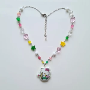 Hello Kitty Skytten  - Handgjort halsband med ett hänge från Sanrio 2013! Jag kan byta ut eller göra om med andra färger, om det önskas!  material som använts är: Rostfritt stål, Glas, plast och akryl pärlor.  Längd är ca 38,5cm och extra längd 4,2cm. 