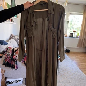 Grön klänning  - Grön lång skjortklänning med knytning i midjan från New Yorker, storlek 34 i materialet viskos (100%). Använd väl men i gott skick. 