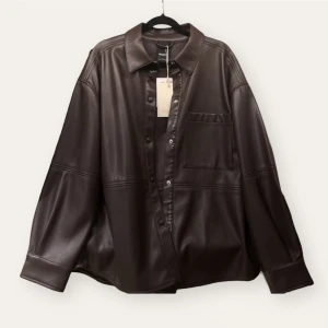 Brun jacka i läderimitation Pull&Bear - Oanvänd brun jacka/skjorta i läderimitation från Pull&Bear med lappen kvar, köpte den för att komma upp i fri frakt men glömde returnera den lol  