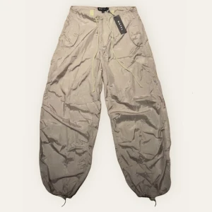 Motel Rocks Chute parachute byxor - Helt oanvända parachute byxor med prislappen kvar från Motel Rocks i färgen Almond Milk, nypris när jag köpte dom var ca 600