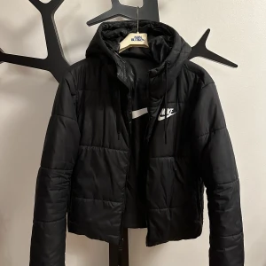 Nike Jacka - Säljer denna svarta Nike vinterjacka då den inte längre kommer till användning. Den går även att vända ut och in, då blir den glansig och med ett större nike märke på ryggen.  Betalning skrev vid swish. 180kr med frakt. 