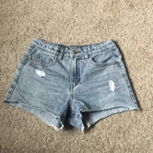 Ljusblåa jeansshorts med hål från Kappahl  - Ljusblåa jeansshorts från Kappahl i strl 158. Ganska använda.