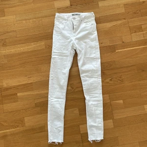 Vita jeans - Superstretchiga vita tighta jeans med slitningar nere vid fötterna. Storlek w26l34. Från topshop modell Jamie. 