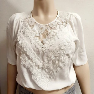 Fetaste spetsblusen från 80-talet!  - Snyggaste toppen från 80-talet med feta axelvaddar!  Vackert krispigt tyg I vad jag tror är någon viskosblandning i kombination med sirliga spetsdetaljer fram och bak. Resår I midjan och dubbla axelvaddar! Så himla fin till jeans eller romantisk långkjol! Ingen märkning förutom tvättråd. Superskick!   Byst: 55x2 Midja: ostretchad: ca 40x2, stretchad: 55x2 Längd: 48 cm  Ärmlängd: 36 cm  Ärmhål: 25x2   