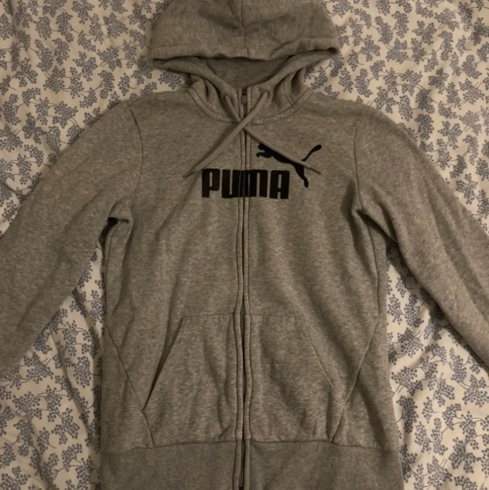 Mellan grå zip up hoodie från märket Puma. Det står XS i plagget men passformen är ganska stor så skulle säga att den mer är en strl S.. Hoodies.