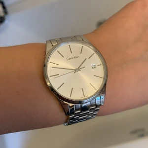 Calvin Klein klocka - Klocka från Calvin Klein i rostfritt stål. Vattentät. Modell K4N 211. Köpt för 2700kr. Saknar den lilla knappen man ändrar tiden med, därav så nedsatt pris. I övrigt är den  i mycket fint skick och sparsamt använd. Går att anpassa storlek efter vrist. 