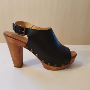 Platåsandaler högklackat träskor läder skinn strl 39 Alberville - Platåsandaler i träsko-stil i äkta läder strl 39. Märke Alberville Italy.  Klackhöjd ca 11cm. Platå i fram ca 3cm hög. Innersula också läder. Använda endast 1 gång, nypris 1500 kr. Har några små skavanker som knappt syns, platån har ett hack i fram sebild