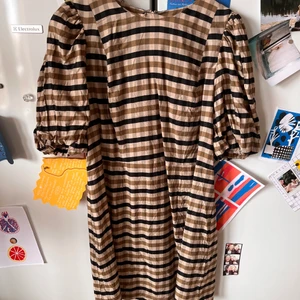 Rutig klänning - Rutig klänning i brunt och svart från H&M. Puffärmar, slutar lite ovan knäna på mig som är 170cm.