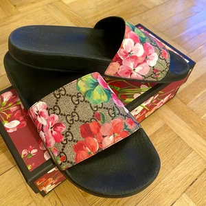 Gucci blooms supreme floral slides  - Säljer dessa supersöta tofflor/slides från Gucci. Inköpta på Guccis hemsida förra året. Endast använda ett fåtal gånger. Storlek 41. RFID kvitto medkommer samt den jättefina boxen. Digitalt kvitto kan visas vid förfrågan. Köpta för 3900 kr, säljs för 1500