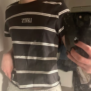 Grå vit randig Levis t-shirt - Helt ny och oanvänd grå vit randig Levis t-shirt. Så härlig grå färg och lite kortare i magen. Jag kan mötas upp i Stockholm eller frakta, köparen står för frakten💕