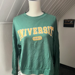 Grön tjocktröja - En grön tjocktröja med tryck. Köpt på Ginatricot i storlek S.