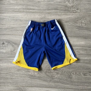 NBA authentic shorts Golden state Warriors  - Golden state warriors shorts från Nike. NBA authentic och ett nyvärde på cirka 800kr. Jättefint skick och passar perfekt med deras blåa Jersey. Storlek M, Tyvärr för små för mig annars hade jag lätt behållt dem. 