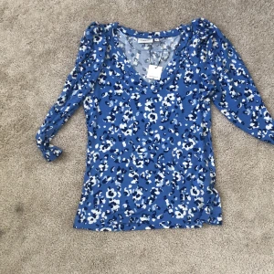 Blommig tröja - Tajt, blommig tröja feån Kappahl. Aldrig använd. Olika blåa nyaner. 