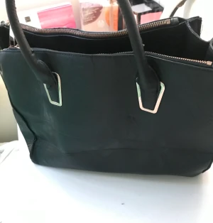 Handväska - En stor svart handväska. Aldrig använd då jag inte använder handväskor. 