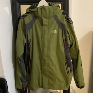 The North face gor-tex regn jacka  - North face jacka med en inbyggd fleece jacka som kan tas ur för varmare väder eller stoppas in för kallare och en avtagbar luva, storleken säger XXL men kan användas från L som en oversized jacka 