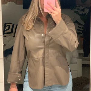 Skinnkavaj/skinnjacka  - Säljer min snygga skinnskjorta från HM i storlek 38 (M) då den inte kommer till användning. Materialet är 100% akryl men ser äkta ut enligt mig! Den har en snygg slits på varje sida vilket gör att den sitter smickrande. Hör av dig vid frågor☺️ 