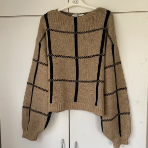 Rutig stickad tröja - Stickad tröja från NA-KD. Köpt här på Plick men säljer vidare då den tyvärr var alldeles för stor för mig (stor i storlek och långa ärmar!). Gott skick!