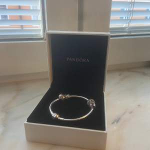 Ett Pandora armband med två pärlor, båda ingår, den ena som är köpt som tillägg går att ta av. Armbandet är oanvänt och kommer med den tillhörande asken.  -Tryck inte på köp nu utan kontakta mig eller förslå pris.
