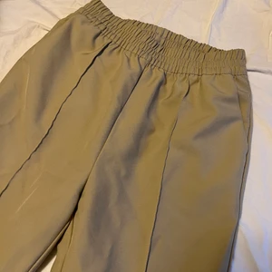 Kostymbyxor NA-KD - Beige kostymbyxor med reså. Känns som mjukisbyxor. Raka i modellen. Storlek S/XS. Mer beige än i bilden. 