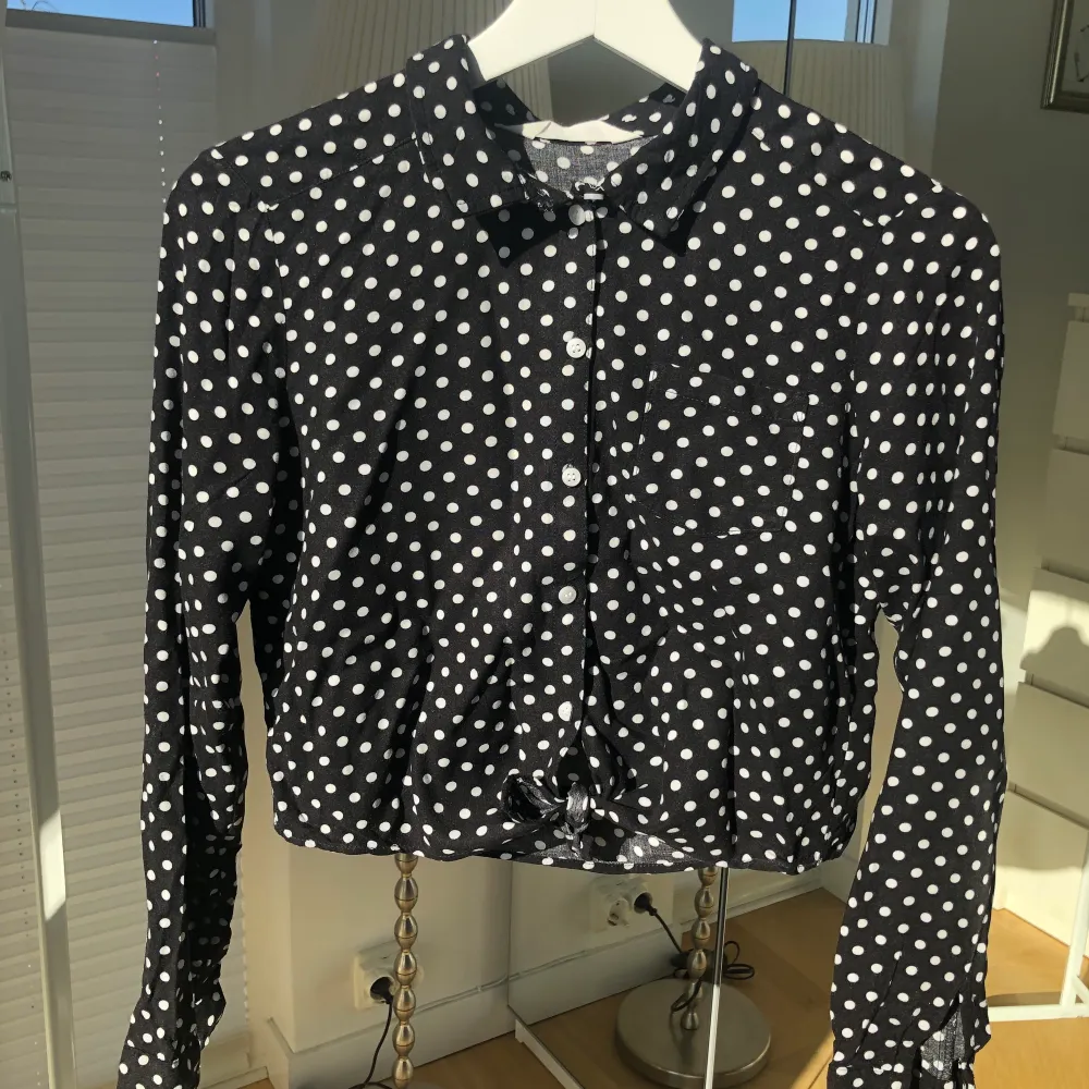 Det är en svart skjorta med vita prickar på. Den är i bra skick och säljs pga att den tyvärr är för liten. Den är från hm och är i storleken 158.  . Skjortor.
