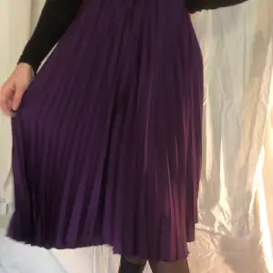 En plisserad lång kjol, i en fin plommon-lila färg. 