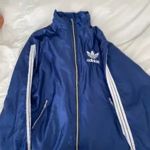 Säljer en skitsnygg mörkblå Adidas windbreaker. Ganska bra skick bara ett litet hål längst ner vid dragkedjan (  meddela  efter fler bilder ) 