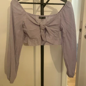 Blå topp knytband knytning långärmad - Fin långärmad topp med knytning fram. Storlek M! Fint skick, använd enstaka gång.